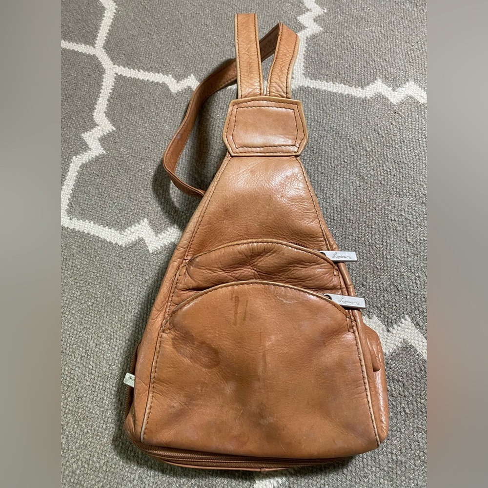 Tan genuine leather backpack style bag with multiple pockets, adjustable straps